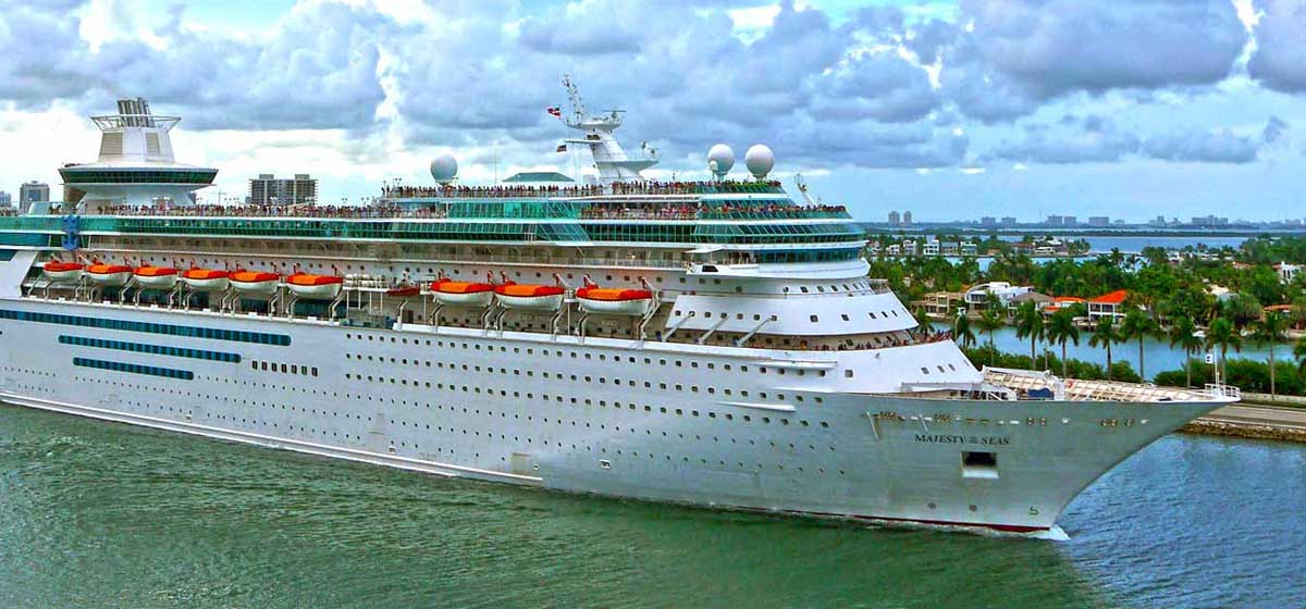 Cruise ship with people on deck heading out to sea