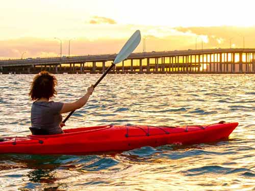 woman in red kayak at sunset