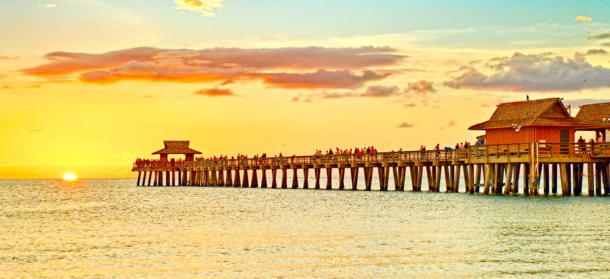 persons enjoying sunset view from long Florida beach pier