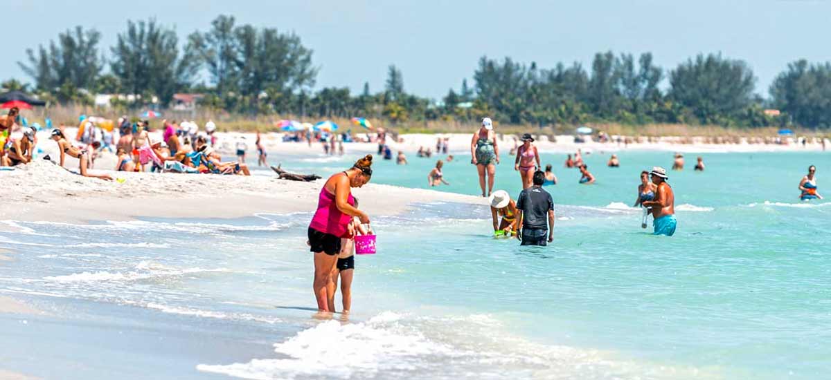 beachgoers enjoying sand and water on sunny florida day