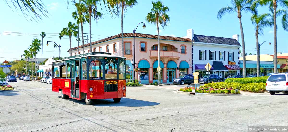red trolley driving with colorful buildings in background